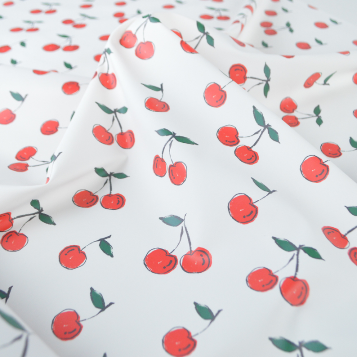 Tissu imperméable type ciré motif cerises fond blanc
